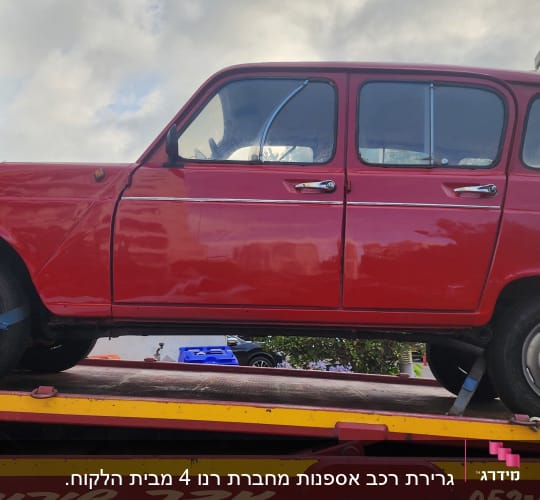 מכונית אדומה על גרר עם רצועות קשירה